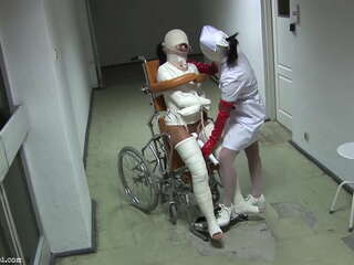 Ziekenhuis-thema BDSM met een rolstoel gebonden patiënt in dwangbuis